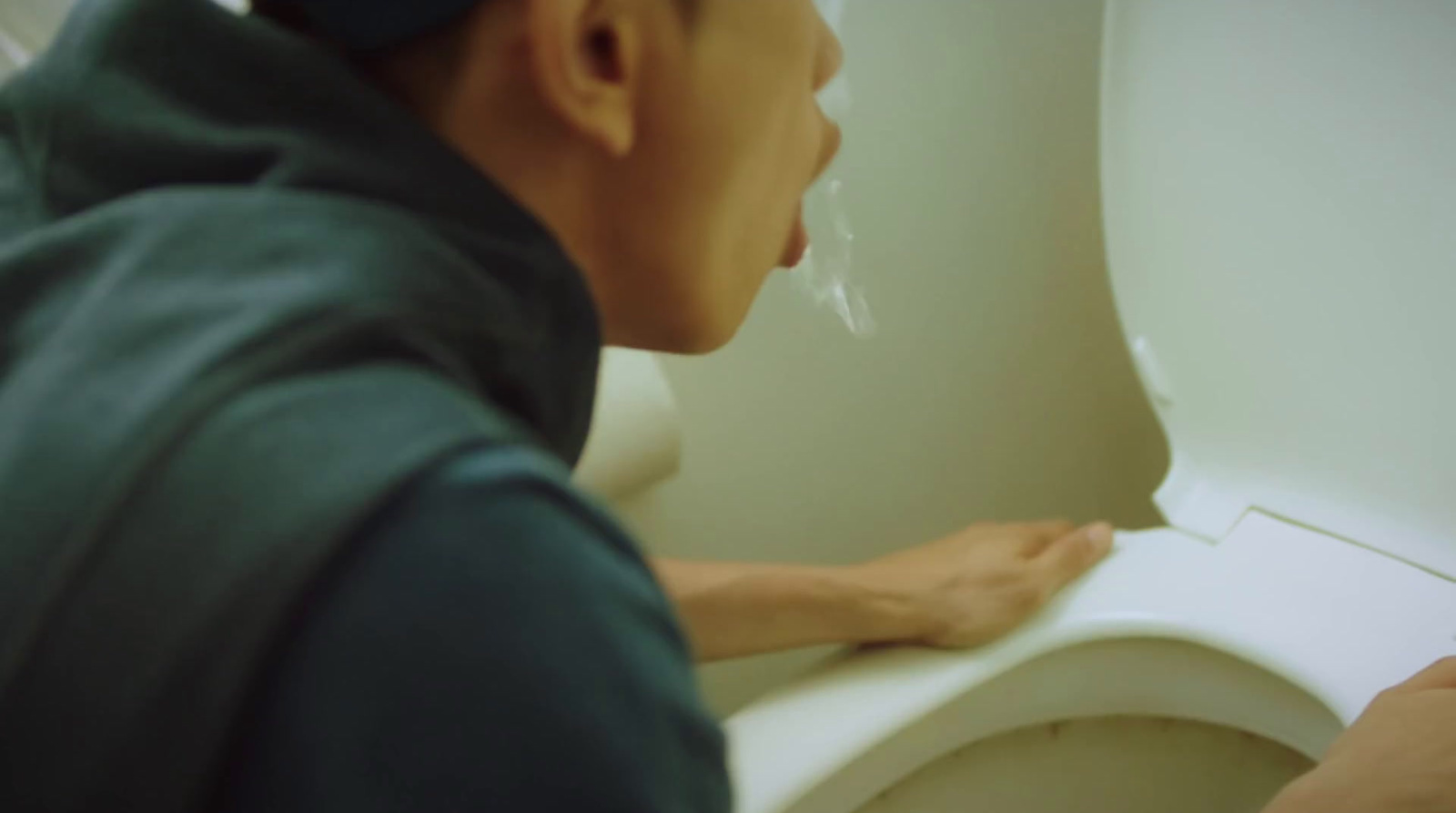 a man in a blue shirt is looking at a toilet