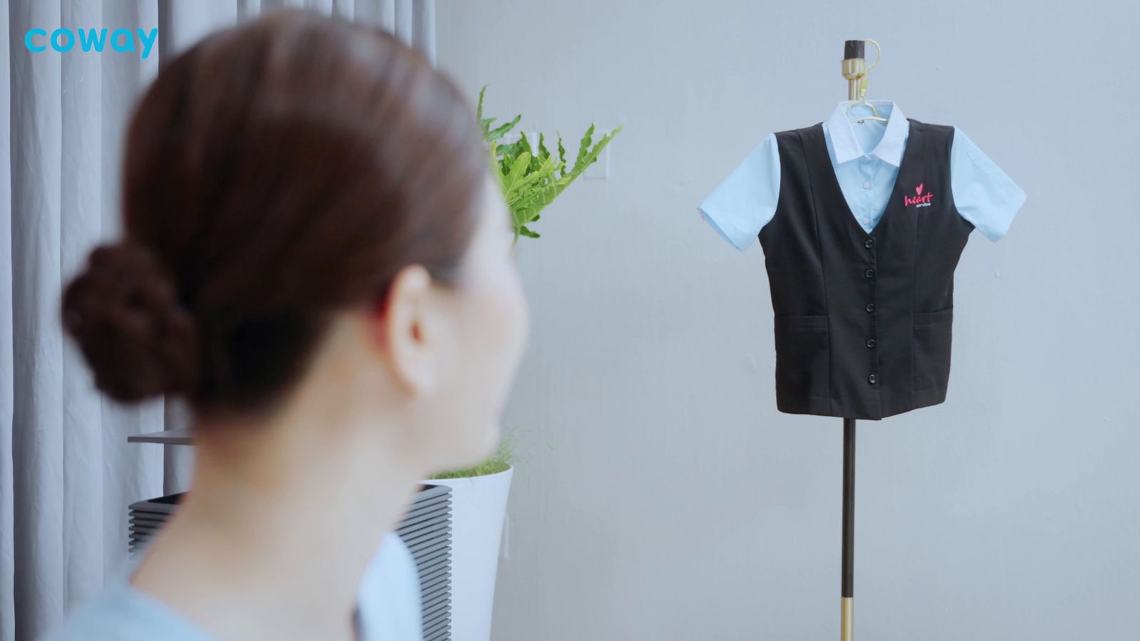 a woman looking at a black vest on a mannequin