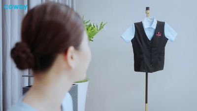 a woman looking at a black vest on a mannequin