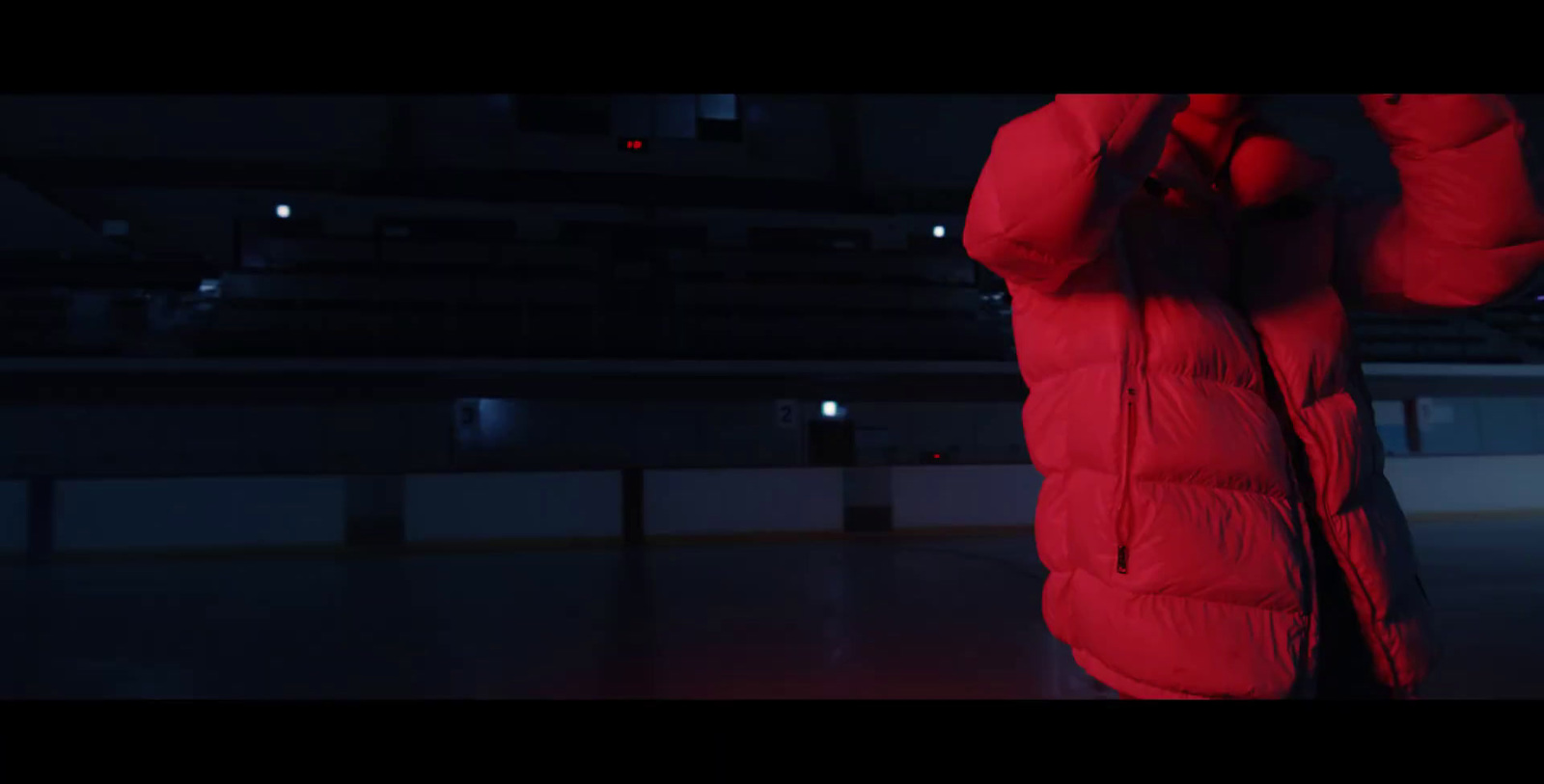 a person in a red coat standing in a dark room