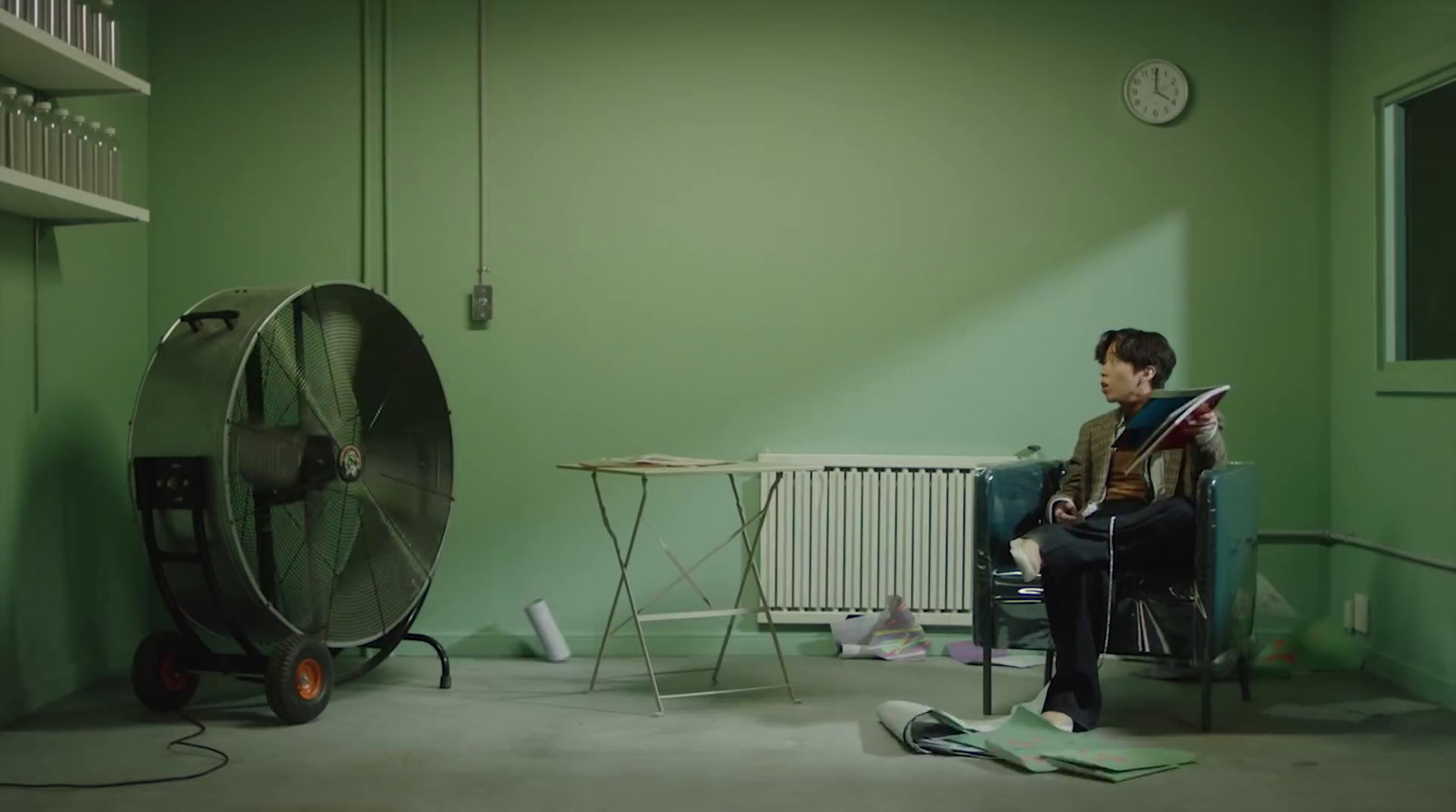 a man sitting in a chair next to a fan