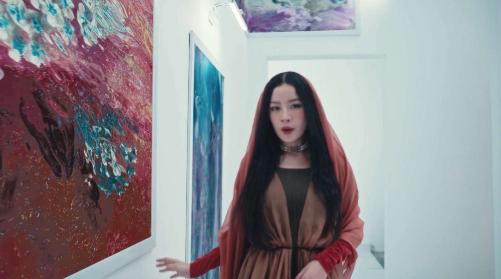 a woman standing in a hallway next to a painting