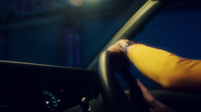 a person driving a car at night with their hand on the steering wheel