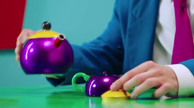 a person in a blue jacket is holding a purple teapot