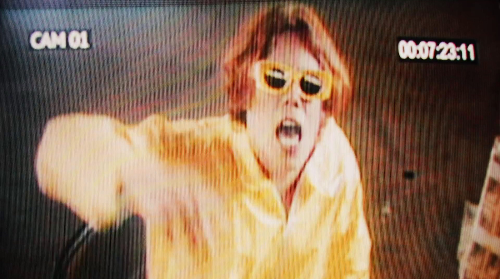 a man in a yellow shirt and sunglasses on a television screen