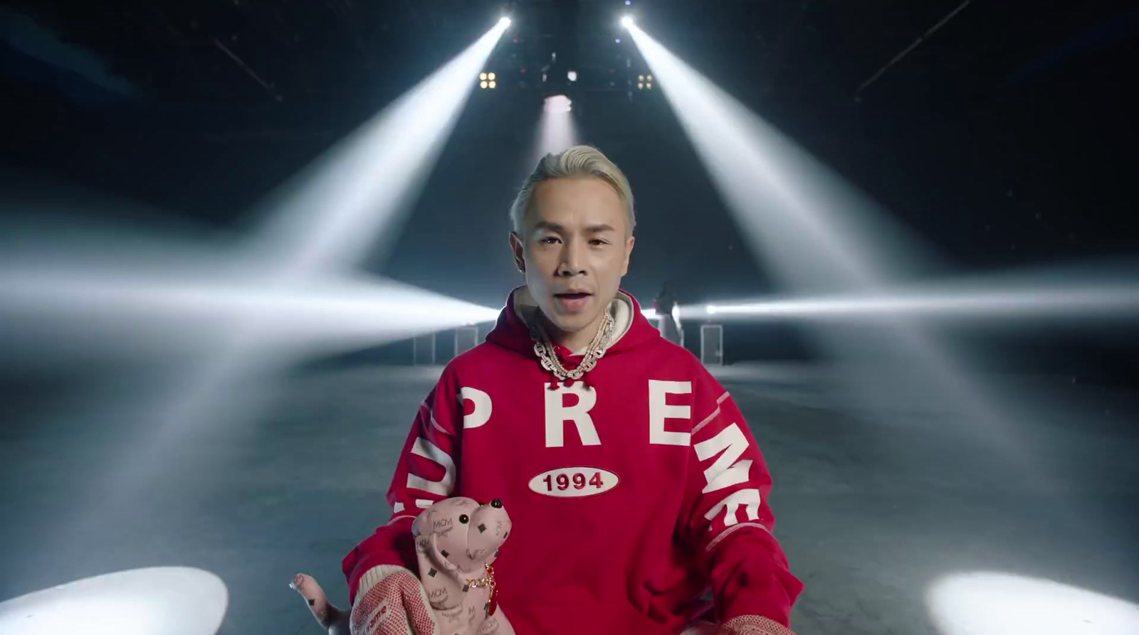 a man in a red hoodie holding a teddy bear