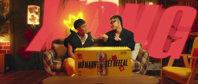 two men sitting on a couch in front of a box