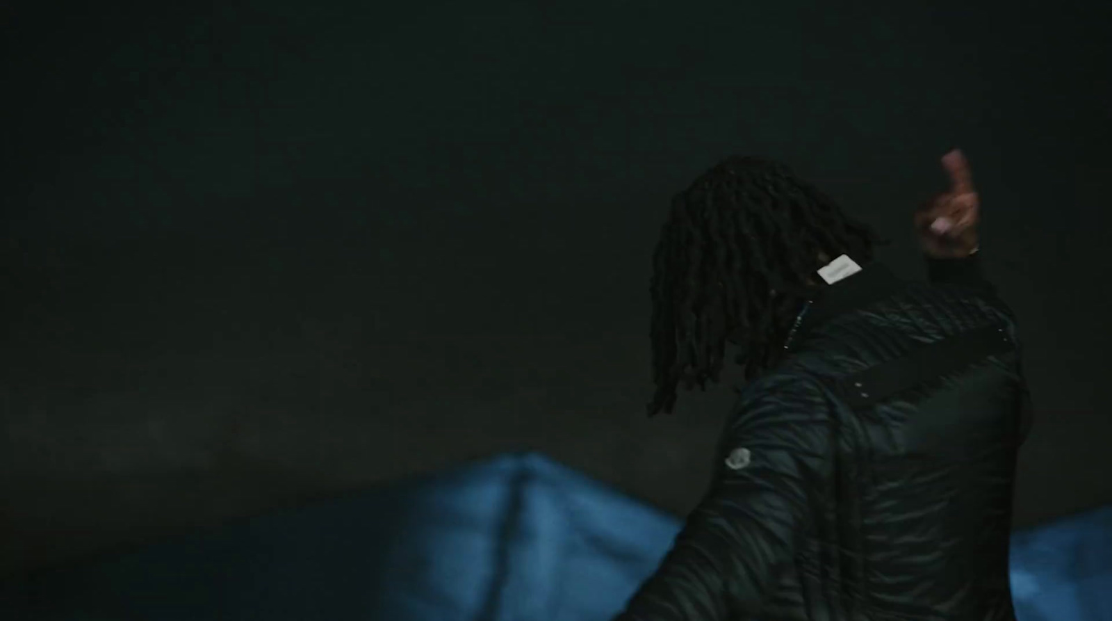 a man with dreadlocks standing in the dark