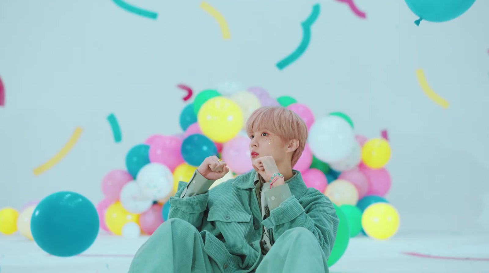 a young boy sitting on the ground surrounded by balloons