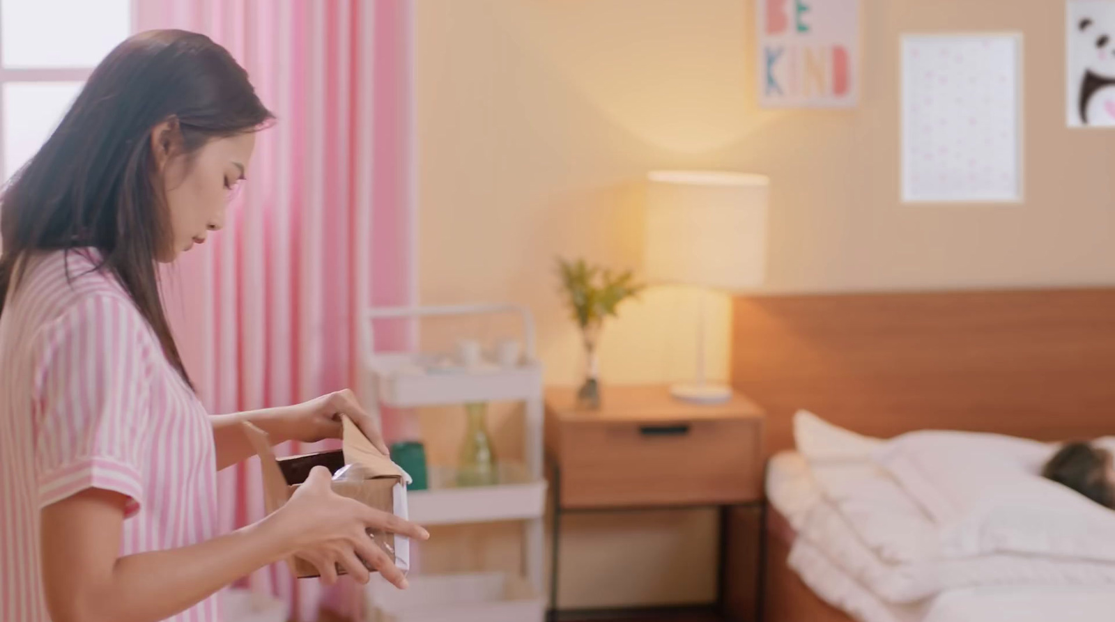 a woman in a pink striped shirt is cleaning a bed