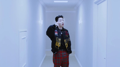 a man in a black jacket and plaid pants standing in a hallway