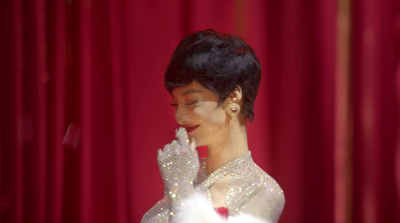 a woman in a white dress and a red curtain