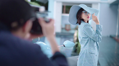 a woman in a blue dress and hat taking a picture