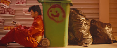 a man sitting on the ground next to a trash can