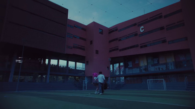 two people standing on a tennis court in front of a building