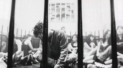 a group of people sitting on the ground behind bars