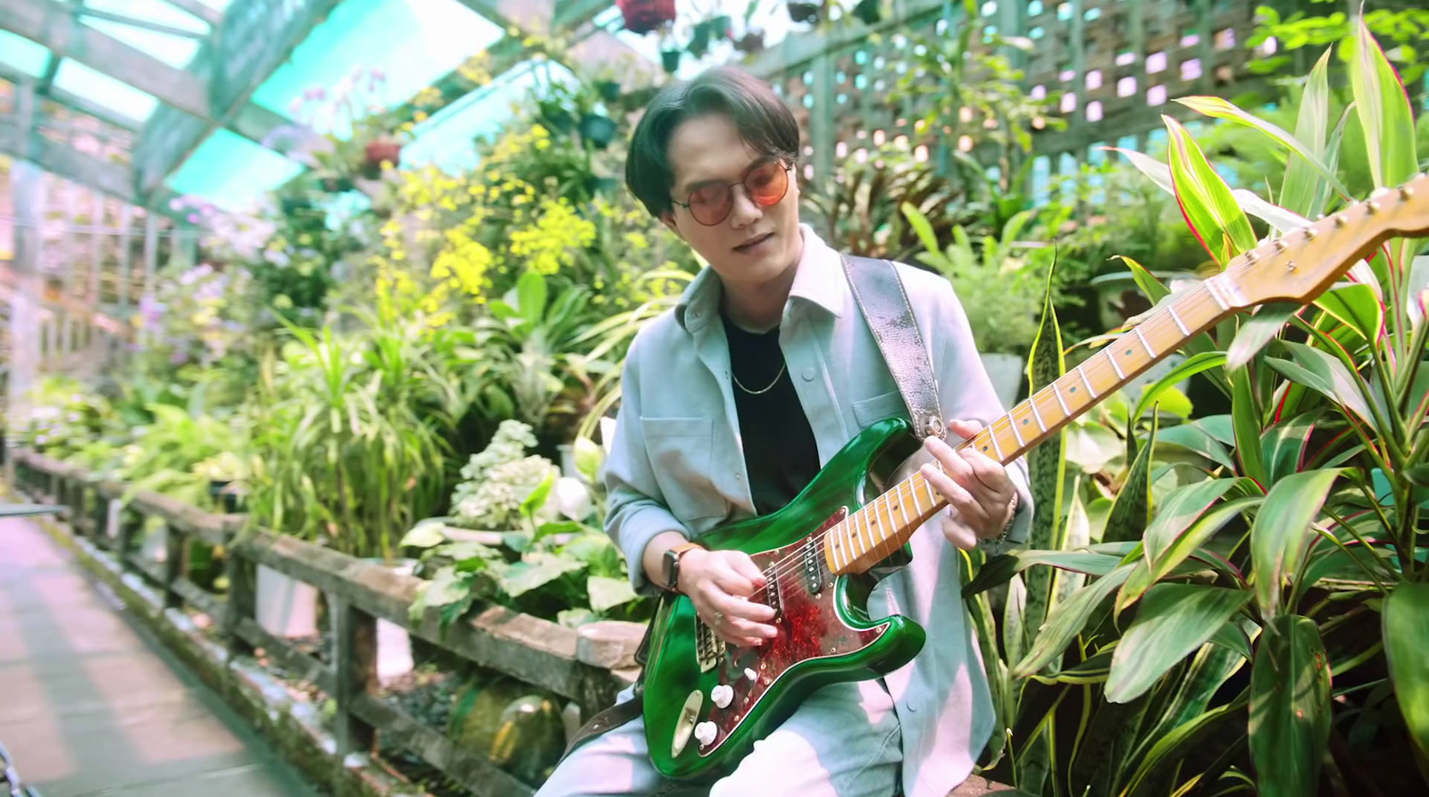 a woman playing a green guitar in a greenhouse