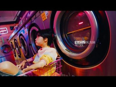 a woman sitting in a shopping cart in front of a washing machine