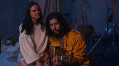 a man playing a guitar next to a woman