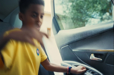 a boy in a yellow shirt is opening the door of a car