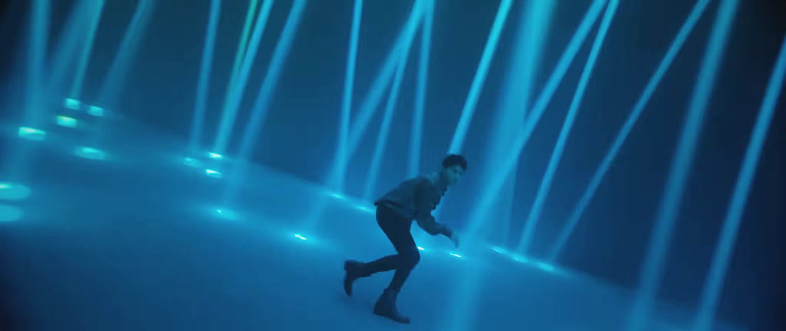 a man is walking through a blue light tunnel