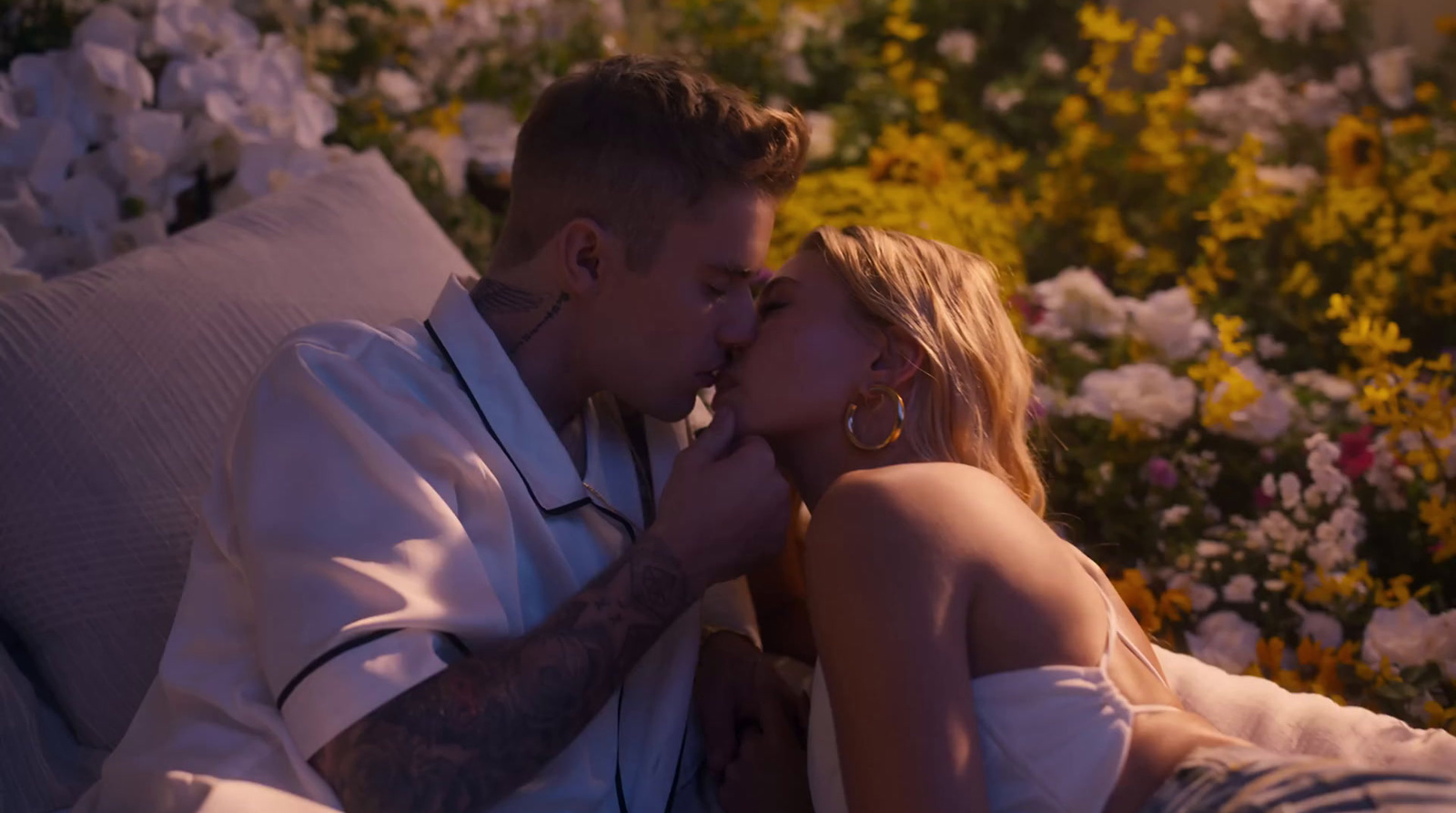 a man and a woman laying on a bed of flowers