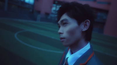 a man in a suit and tie standing in front of a soccer field