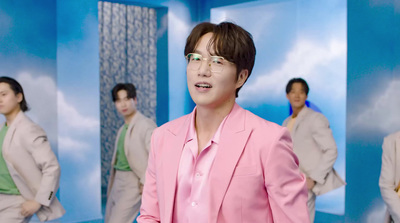 a man in a pink suit standing in front of a blue wall