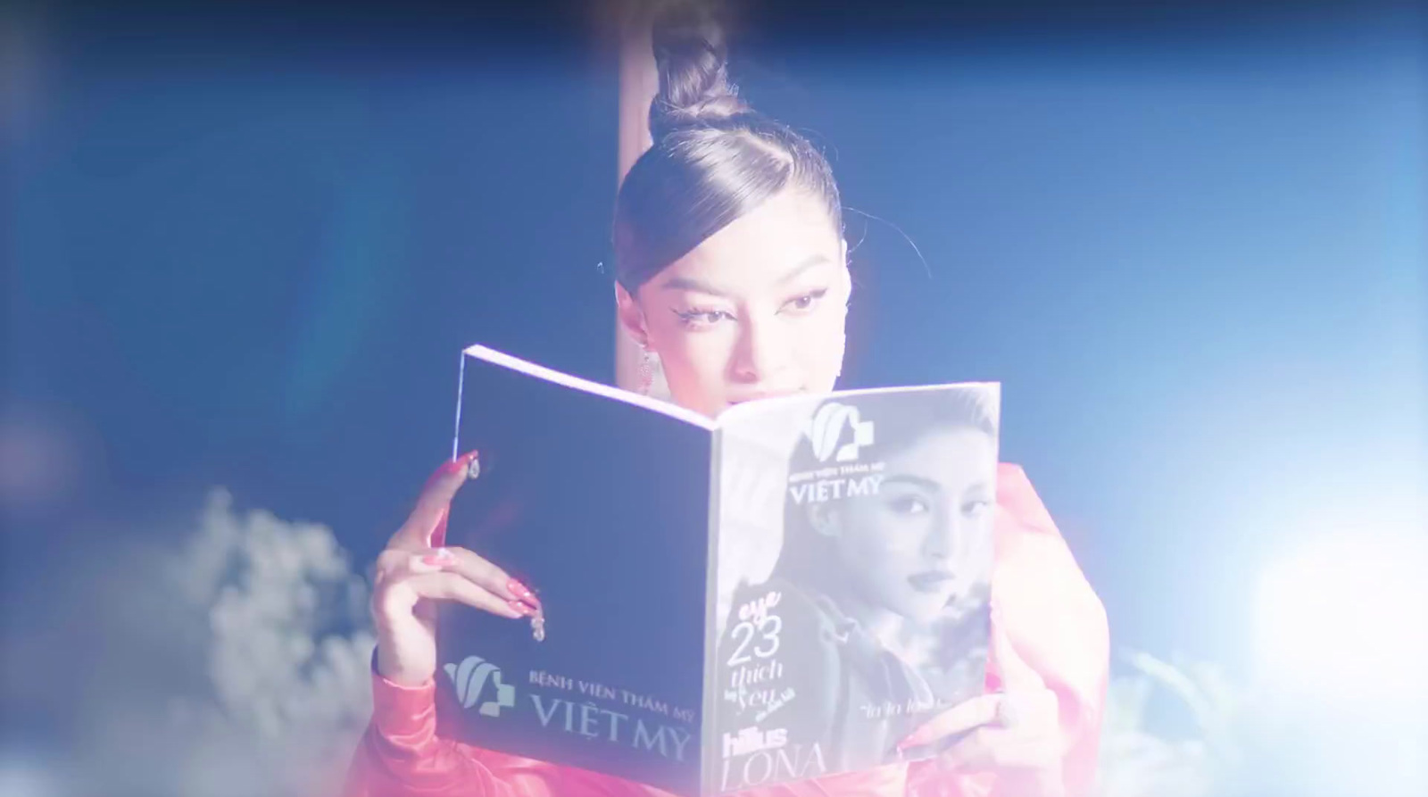 a woman reading a book in front of a blue background