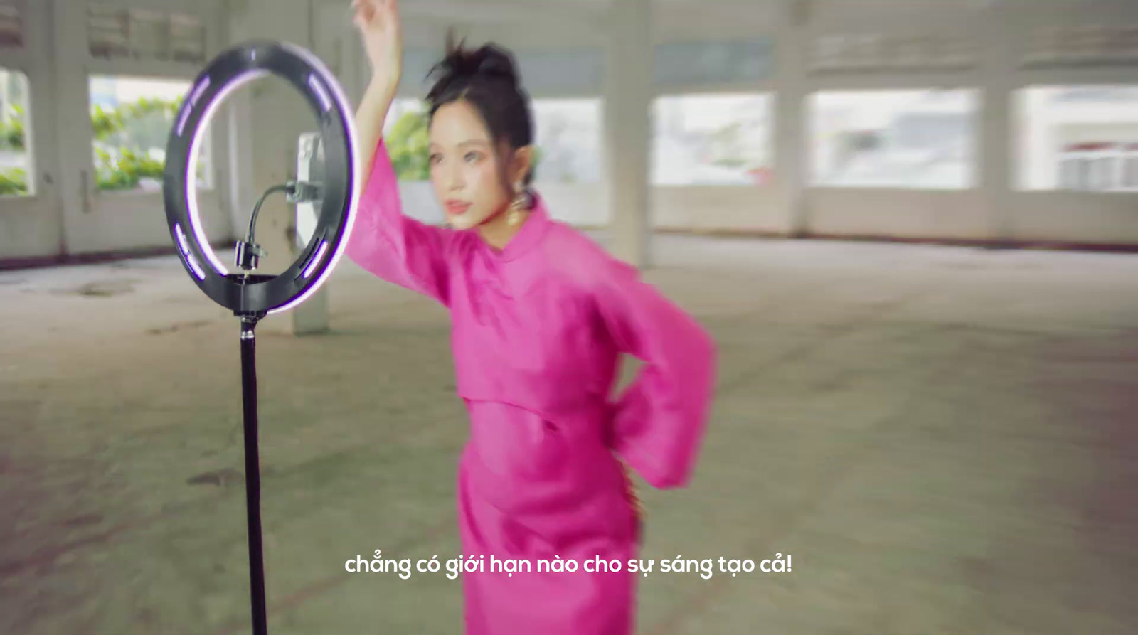 a woman in a pink dress standing in front of a camera