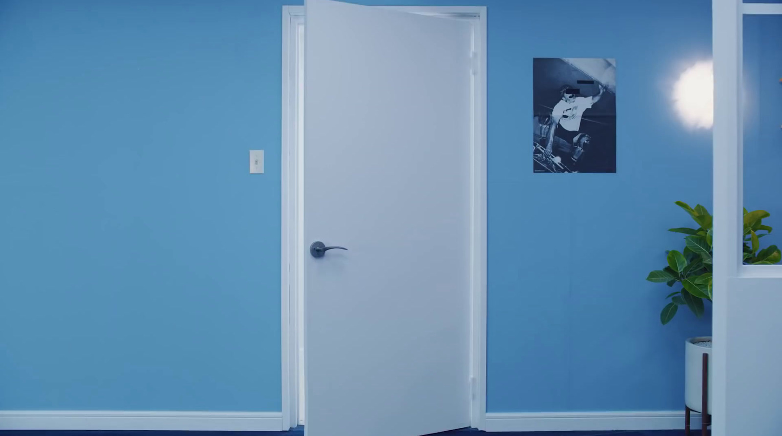 a blue room with a white door and a potted plant