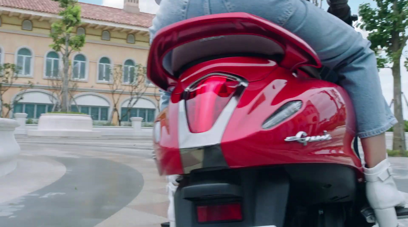 a woman riding a red motorcycle down a street