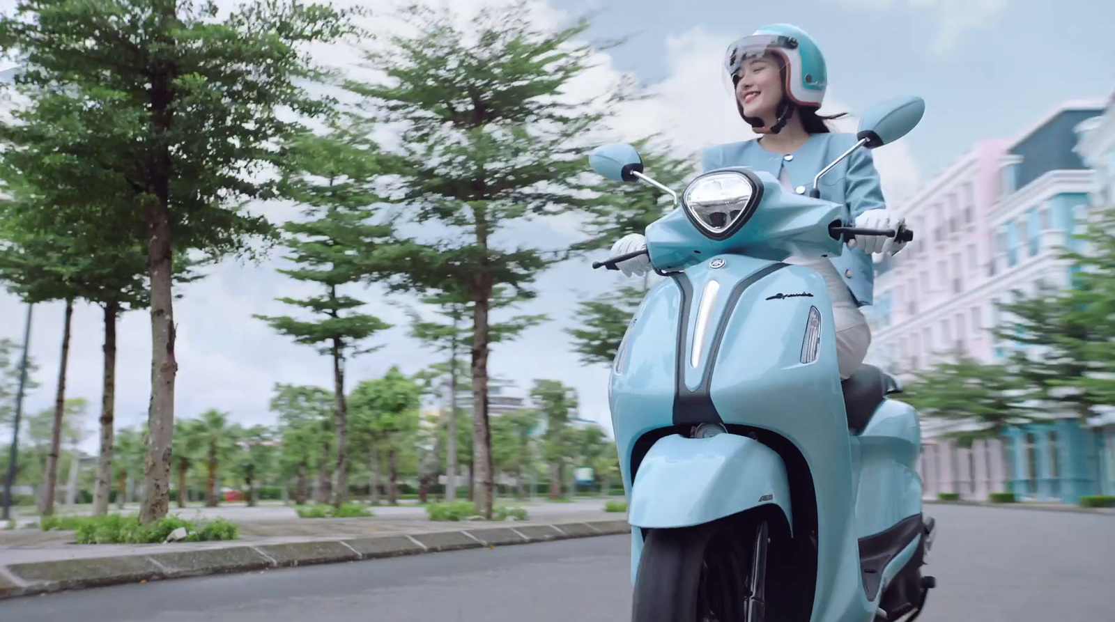 a woman riding a blue motorcycle down a street