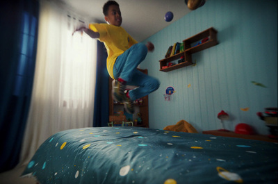 a boy jumping on a skateboard in a bedroom