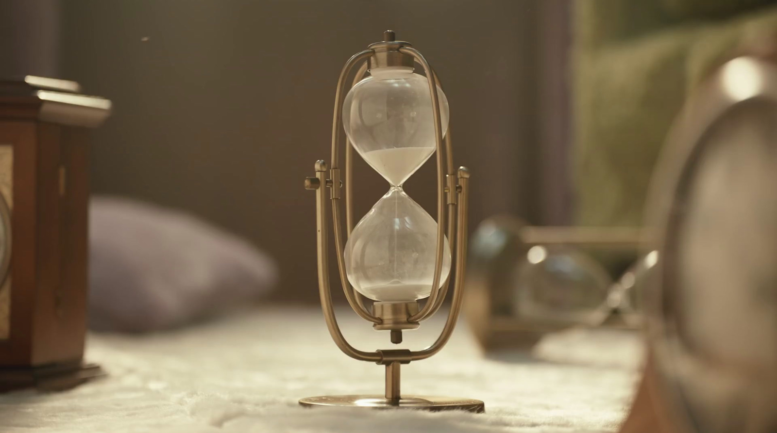 an hourglass sitting on top of a table next to a clock