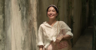 a woman standing in an alley with a basket in her hand