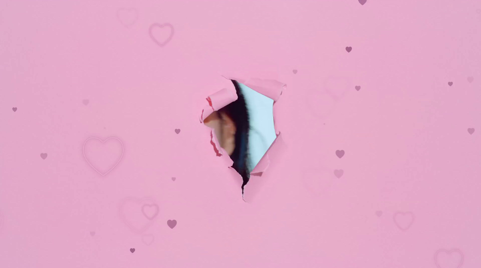 a hole in a pink paper with hearts on it