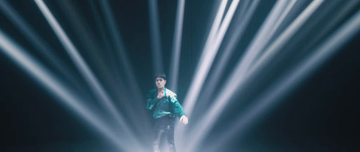 a man standing on a stage with a lot of lights behind him