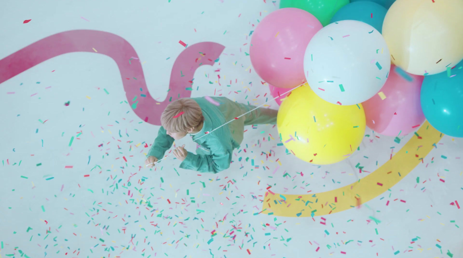 a little boy standing in front of a bunch of balloons