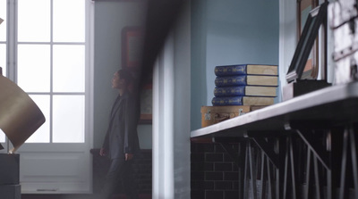 a woman standing in a room next to a stack of books