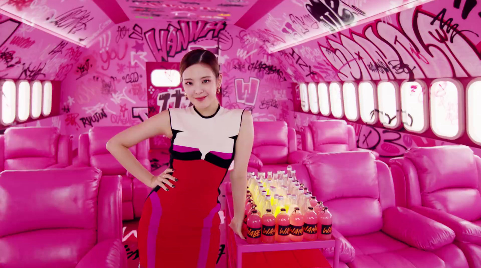 a woman standing in front of a cake in a pink room