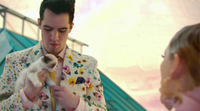 a man in a floral suit holding a kitten