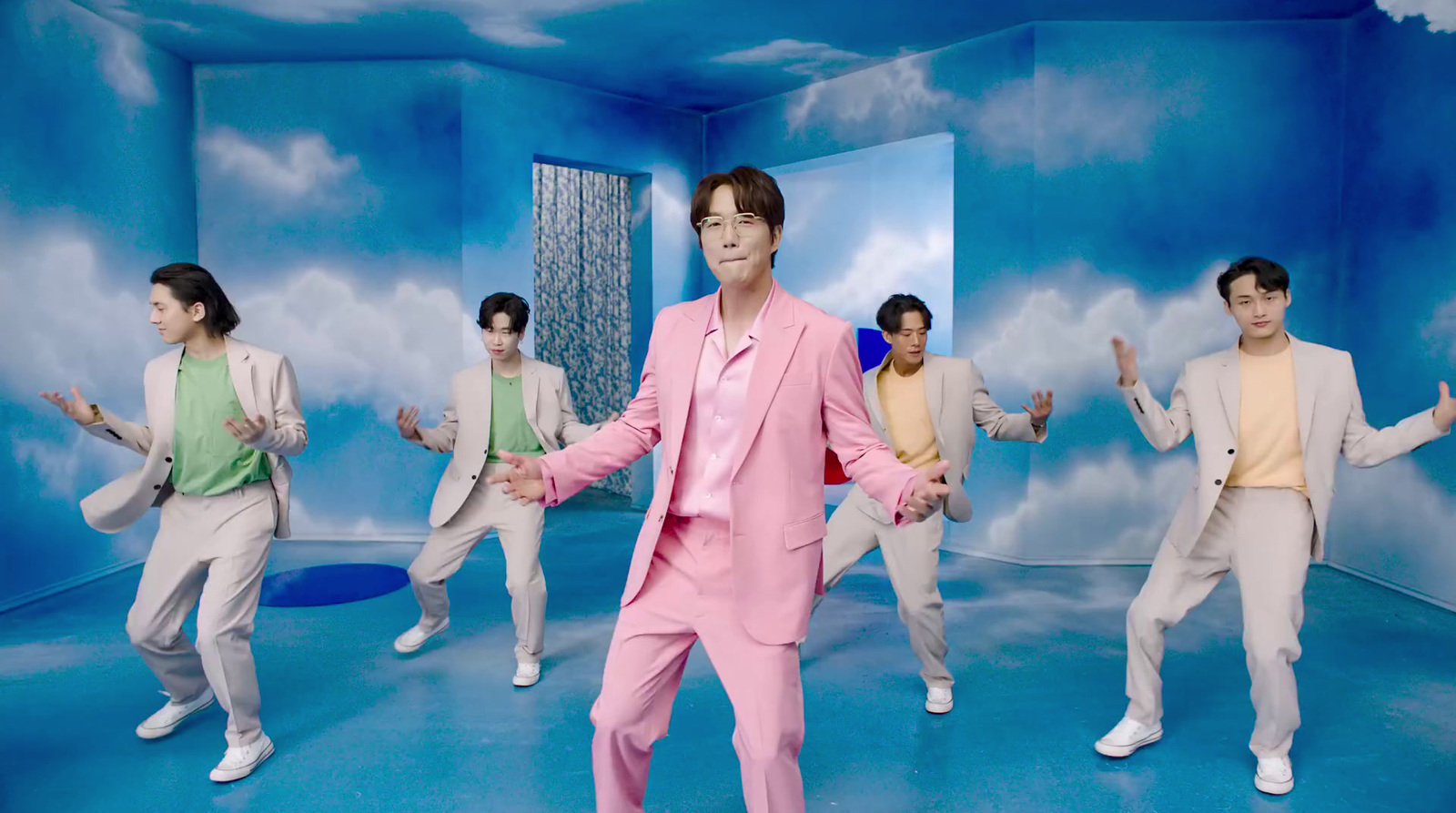 a man in a pink suit standing in front of a group of other men