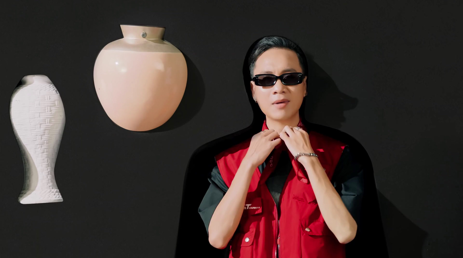 a man wearing sunglasses standing next to a vase