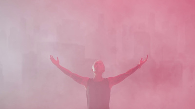 a man standing in front of a pink smoke bomb