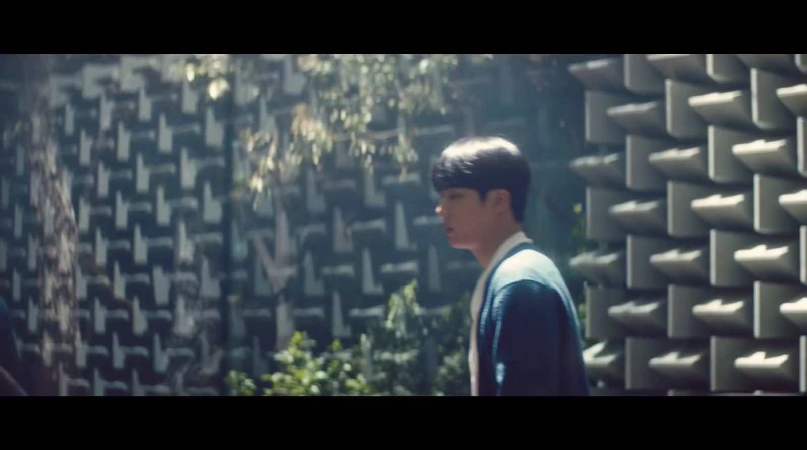 a young man standing in front of a wall