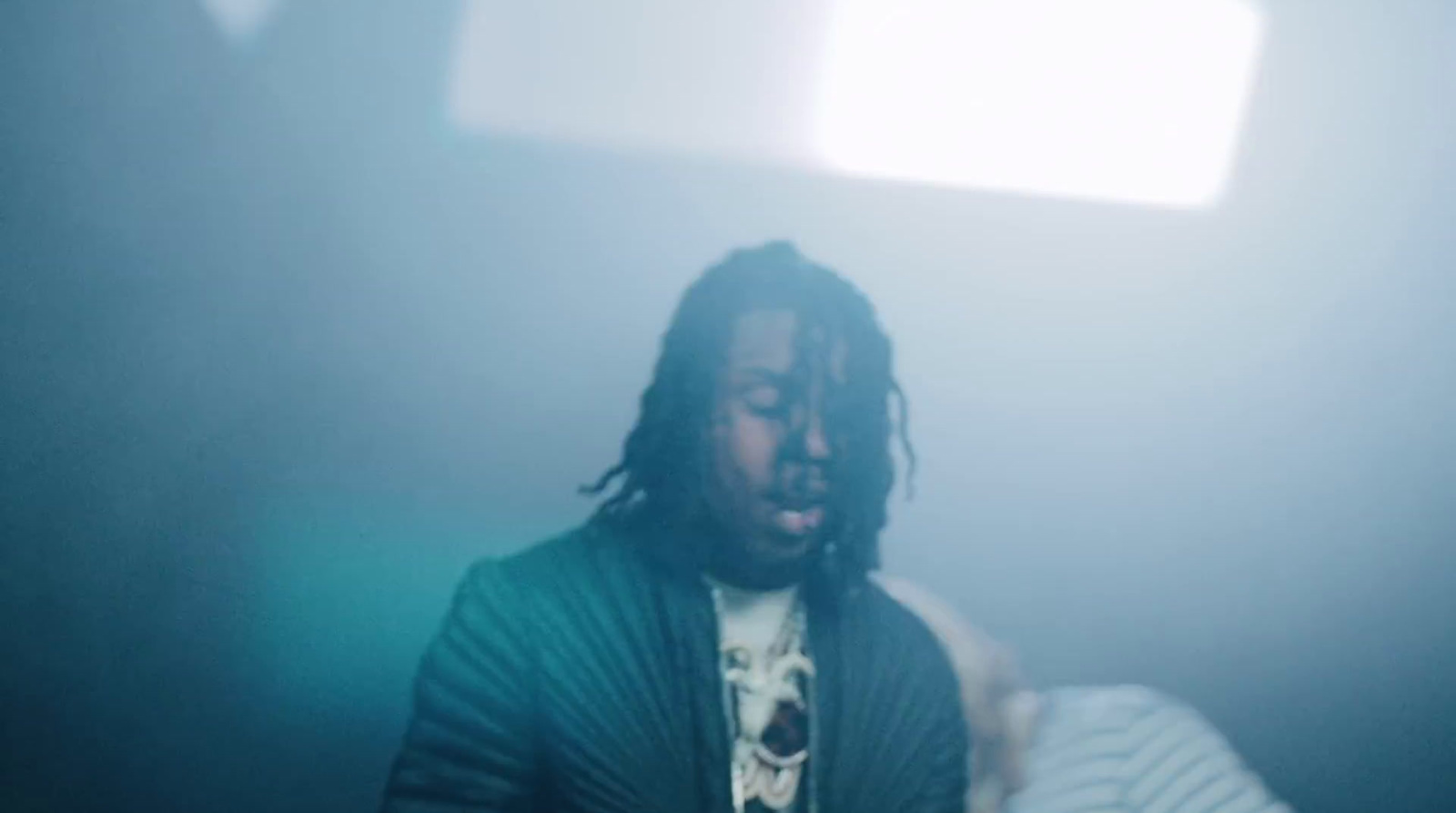 a man with dreadlocks standing in a dark room