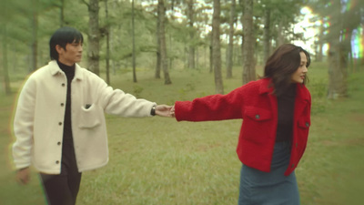 a man and a woman holding hands in the woods