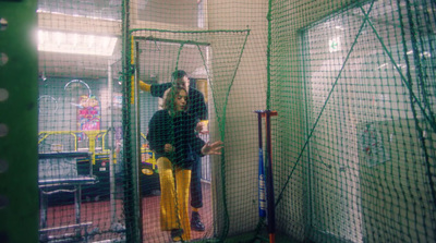 a man and a woman standing in a batting cage