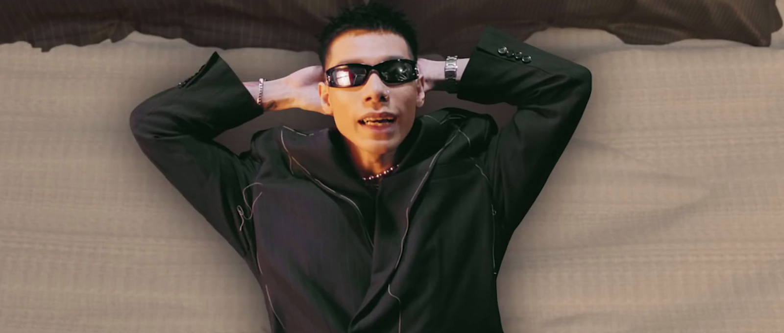 a man in sunglasses laying on top of a bed